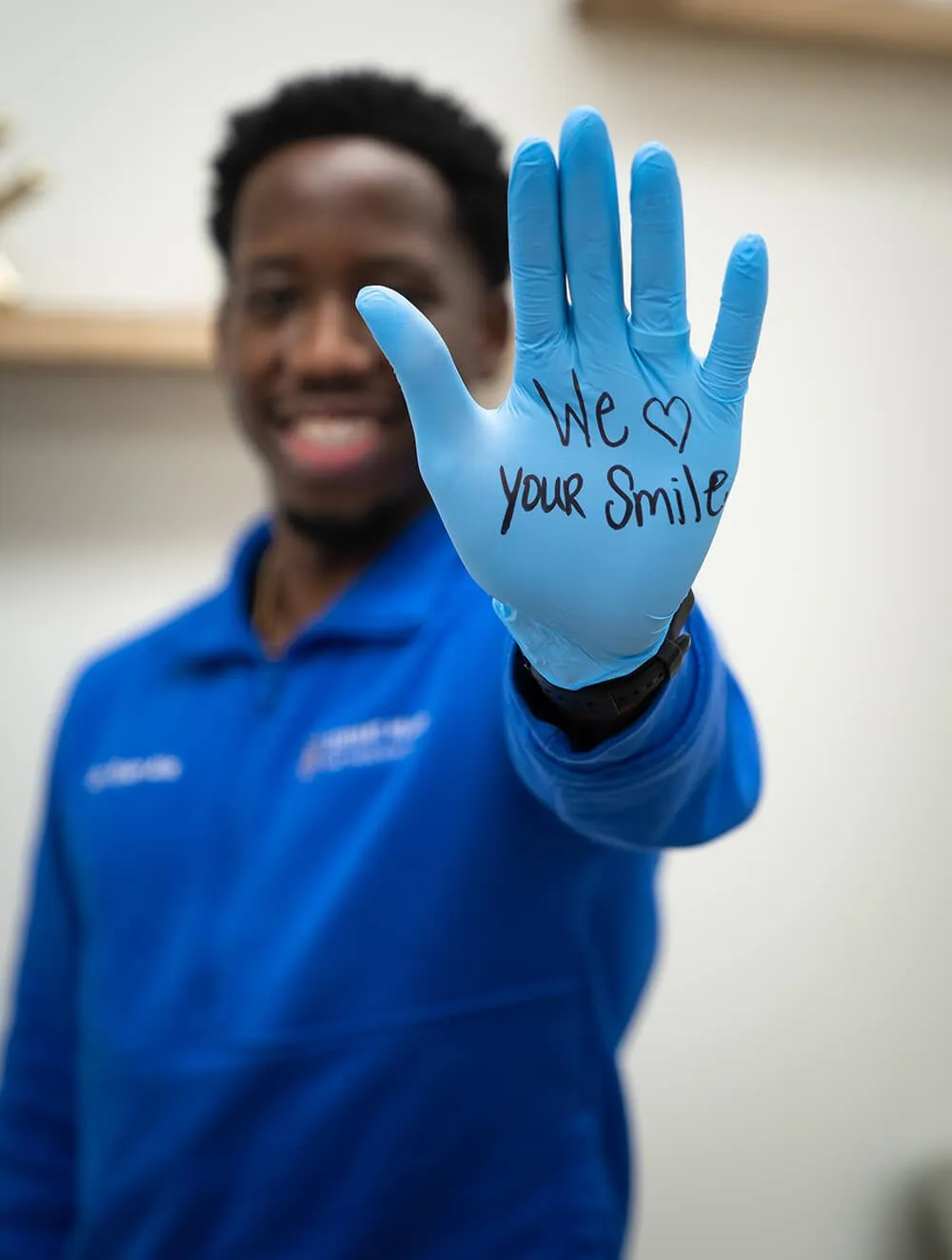 Dr. Ryan Allo holding up a glove reading We Love Your Smile at Servant Heart Orthodontics