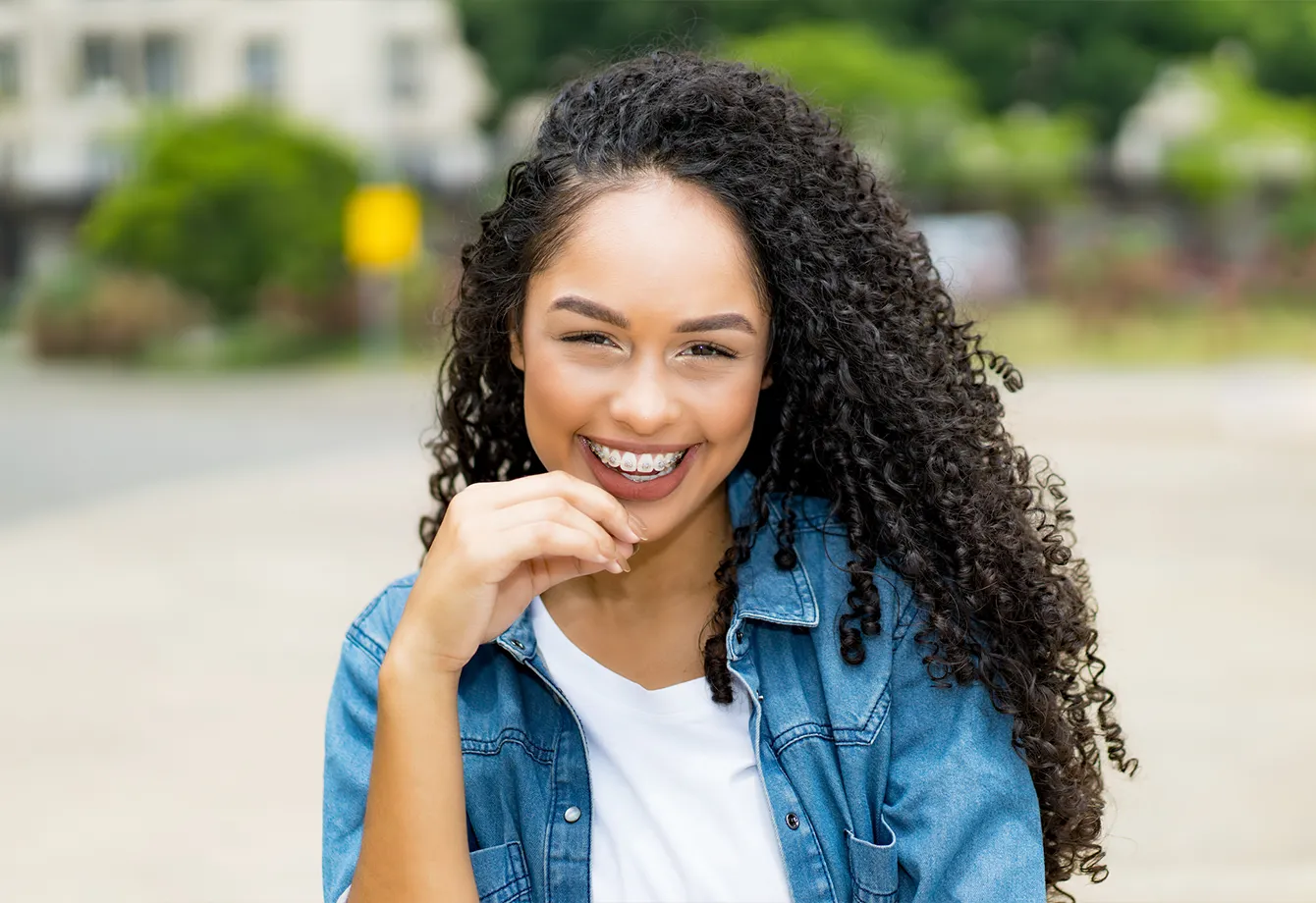 Young woman smiling with braces on her teeth outdoors